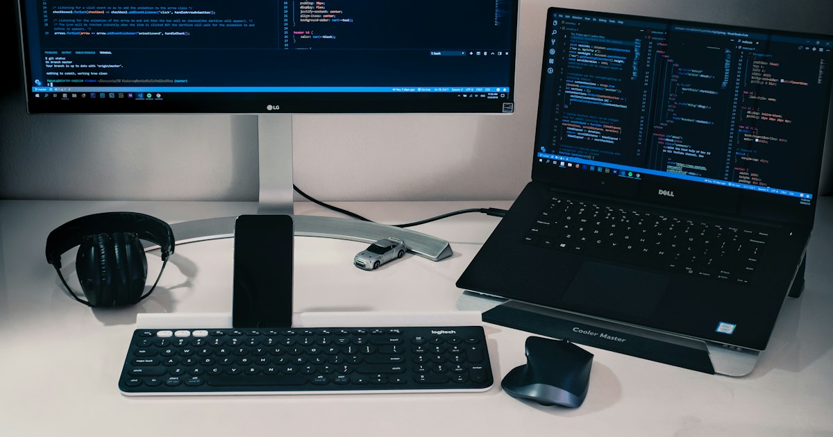 Ekranında kod açık bir dizüstü bilgisayar ve monitör bulunan geliştirici masası